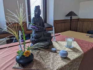 Japanese style flower arrangement with grasses and flowers on a Zen altar featuring Kuan Yin.